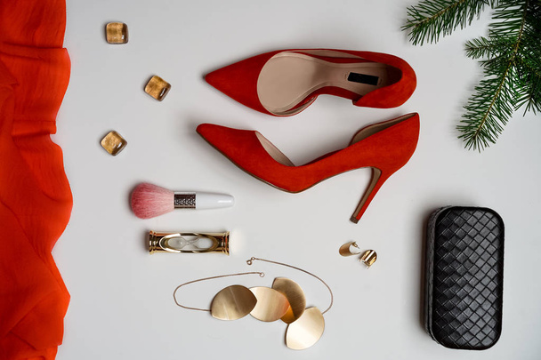 Flat lay to new year and christmas party outfit composition red shoes accessories jewelry clutch fir tree with balls white background. Party date night conception. Top view, vertical, horizontal - Zdjęcie, obraz