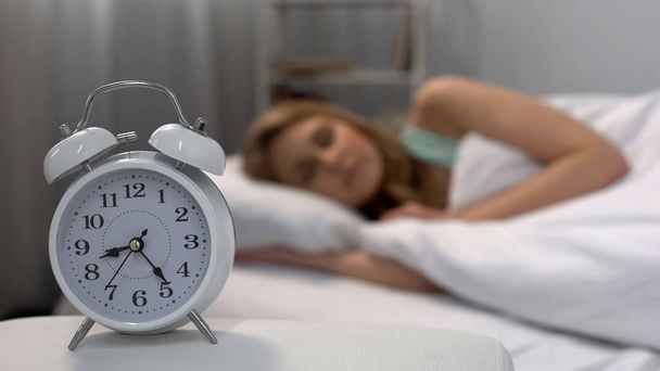 Woman oversleeping in morning, alarm clock ringing near bed, daily routine - Foto, Imagem