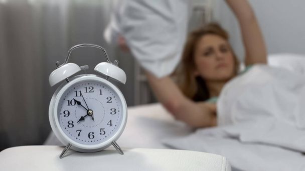 Annoyed with alarm clock lady throwing pillow, sleep deprivation, morning stress - Фото, зображення