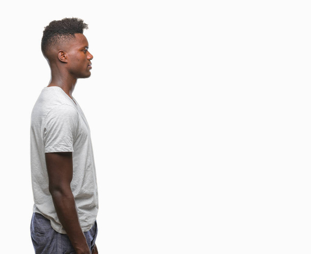 Молодой африканский американец на изолированном фоне глядя в сторону, расслабиться профиль позировать с естественным лицом с уверенной улыбкой
. - Фото, изображение