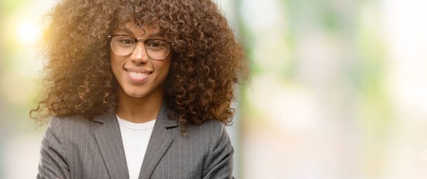 Afro-amerikai üzleti nő visel szemüveget boldog arca mosolygós, átlépte a fegyverek néz a kamerába. Pozitív embernek. - Fotó, kép