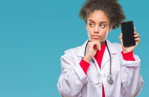 İzole arka plan ciddi bir yüz düşünme hakkında soru, çok karışık bir fikir üzerinde akıllı telefon kullanan genç afro Amerikalı doktor kadın - Fotoğraf, Görsel