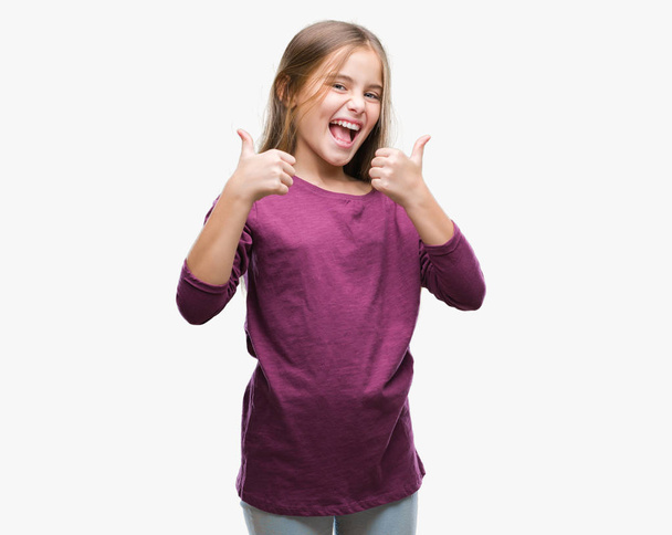 Young beautiful girl over isolated background success sign doing positive gesture with hand, thumbs up smiling and happy. Looking at the camera with cheerful expression, winner gesture. - Photo, Image