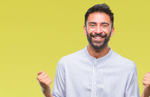 Adult hispanic man over isolated background celebrating surprised and amazed for success with arms raised and open eyes. Winner concept. - Photo, Image