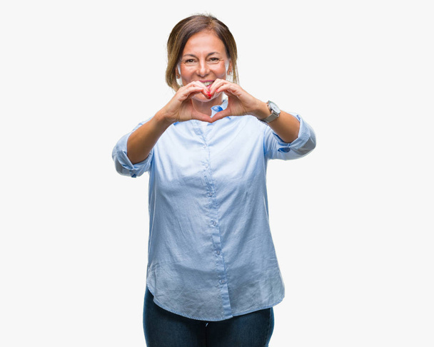 Mulher hispânica sênior de meia idade sobre fundo isolado sorrindo no amor mostrando símbolo do coração e forma com as mãos. Conceito romântico
. - Foto, Imagem