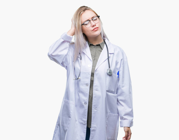 Young blonde doctor woman over isolated background confuse and wonder about question. Uncertain with doubt, thinking with hand on head. Pensive concept. - Foto, Imagem