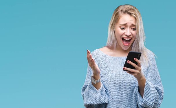 Jeune femme blonde envoyer un message par SMS en utilisant un smartphone sur fond isolé très heureux et excité, expression gagnante célébrant la victoire en criant avec un grand sourire et les mains levées
 - Photo, image