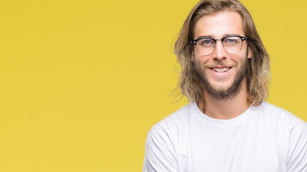Young handsome man with long hair wearing glasses over isolated background happy face smiling with crossed arms looking at the camera. Positive person. - Photo, Image