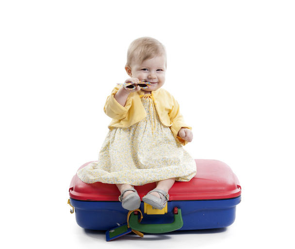 little baby girl seated on a red and blue suitcas - Foto, Imagen