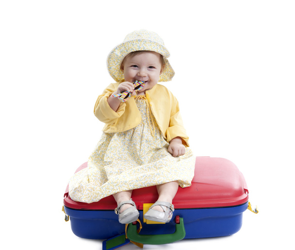 little baby girl seated on a red and blue suitcas - Photo, Image