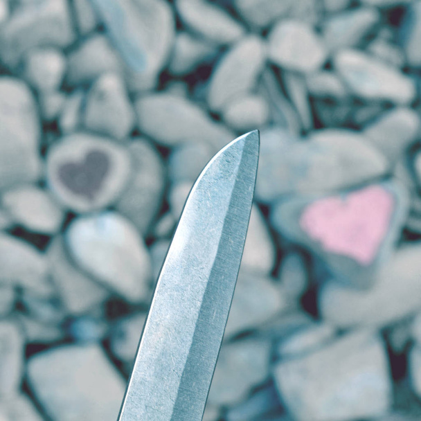 Cortando faca mergulho coração rosa pintado com batom em pedaço de pedra. Símbolo do fim do amor e de duas pessoas separam-se e divórcio
 - Foto, Imagem
