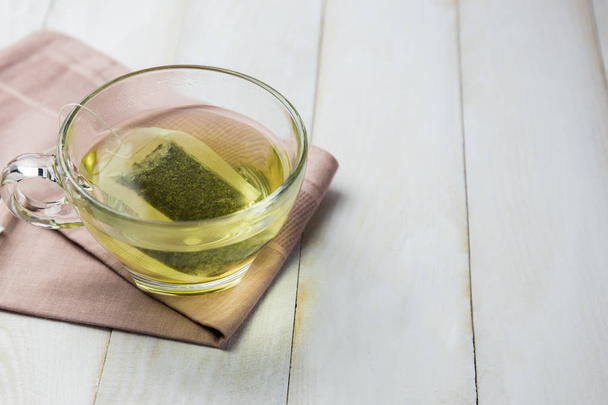Ζεστό τσάι πράσινο γυαλί που τοποθετείται σε λευκό ξύλινο πάτωμα. - Φωτογραφία, εικόνα
