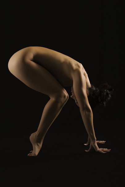 Side profile of a naked woman exercising - Foto, afbeelding