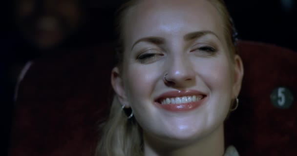 Detailní záběr mladá žena s úsměvem do sebe jako ona sleduje a má dobrý film. - Záběry, video