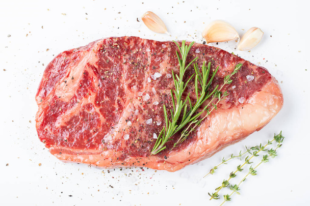 Raw striploin beef steak with rosemary, thyme, salt and pepper. isolated against white. top view. - Φωτογραφία, εικόνα