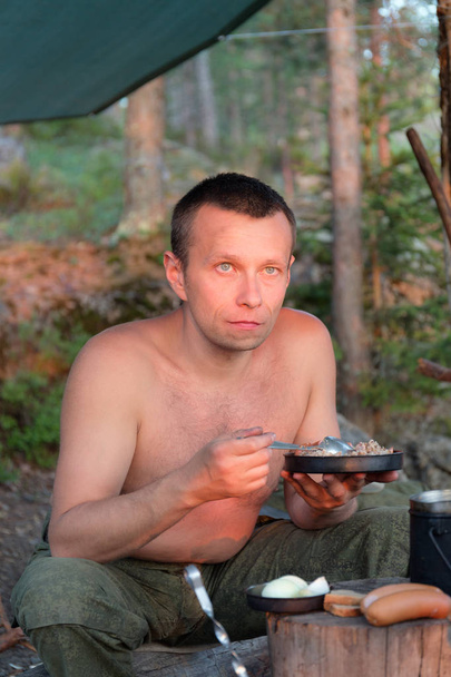 man met diner in het bos kamp de zonsondergang bewonderen - Foto, afbeelding