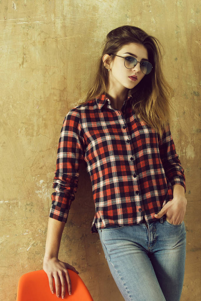 Csinos lány piros kockás inget és farmert visel szemüveget - Fotó, kép