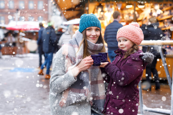 Kleine süße Tochter und Mutter mit einer Tasse dampfender heißer Schokolade oder Kinderpunsch - Foto, Bild
