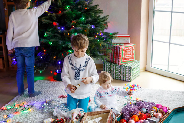 Deux petits garçons et adorable petite fille décorant l'arbre de Noël avec de vieux jouets vintage et des boules
. - Photo, image