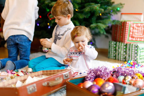 Deux petits garçons et adorable petite fille décorant l'arbre de Noël avec de vieux jouets vintage et des boules
. - Photo, image