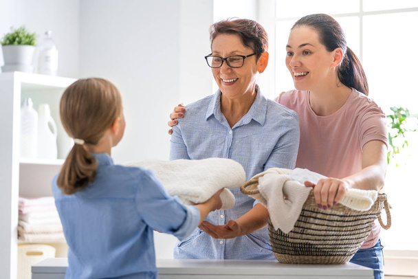 Beautiful women and child girl little helper are having fun and smiling while doing laundry at home. - 写真・画像