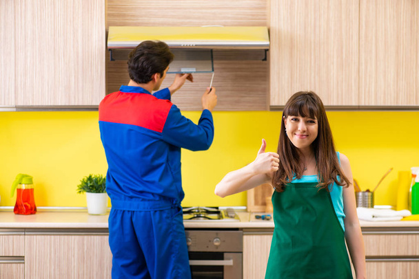 Frau diskutiert mit Bauunternehmer in Küche über Reparatur - Foto, Bild