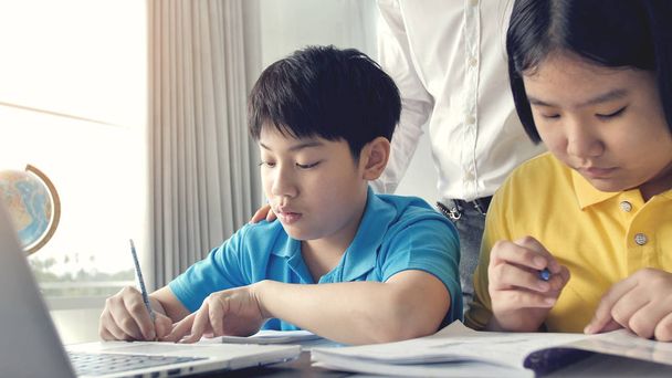 Tutor bambini in classe che imparano sul computer portatile con insegnante. Asiatico bambino apprendimento con insegnante a casa
. - Foto, immagini