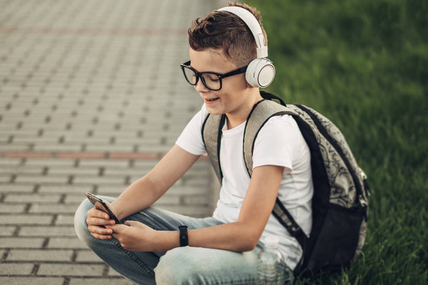 Retrato de niño escuchando música con auriculares Withe al aire libre
 - Foto, imagen