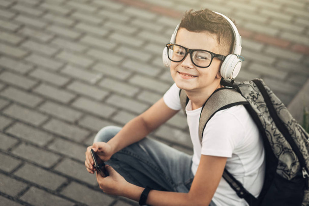 Προσωπογραφία αγοριού, να ακούτε μουσική με ακουστικά βέργα σε εξωτερικούς χώρους - Φωτογραφία, εικόνα