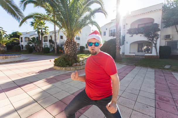Fêtes et concept de personnes - homme drôle dans le chapeau de Noël dansant en plein air
 - Photo, image
