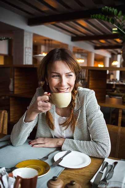 Young woman drinking cup of coffee in cafe - Foto, Imagem