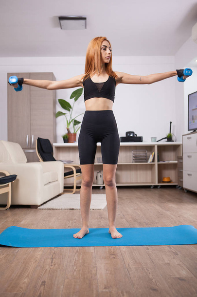 Fit girl doing lateral shoulder rises in her home training progam - Zdjęcie, obraz