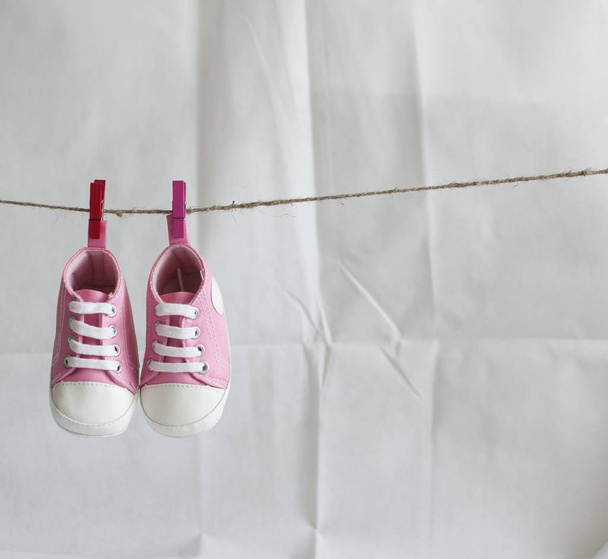 Детская обувь и фотография, висящая на линии одежды на белом фоне
 - Фото, изображение