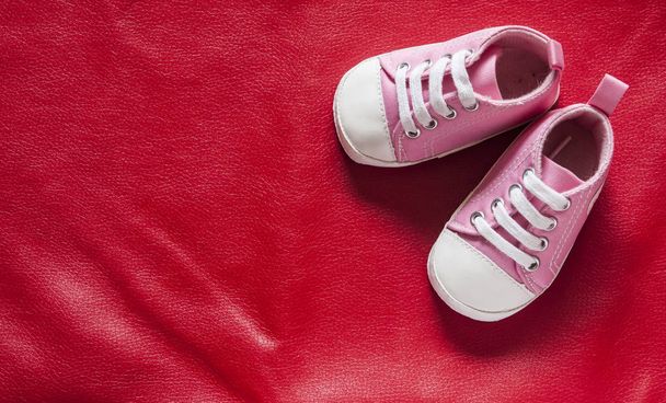 Sapatos pequenos bonitos do bebê no fundo de couro vermelho com espaço de cópia para o seu texto
 - Foto, Imagem