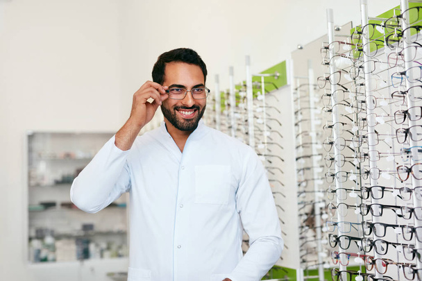 Optician Man Near Showcase With Eyeglasses At Glasses Shop - Foto, afbeelding
