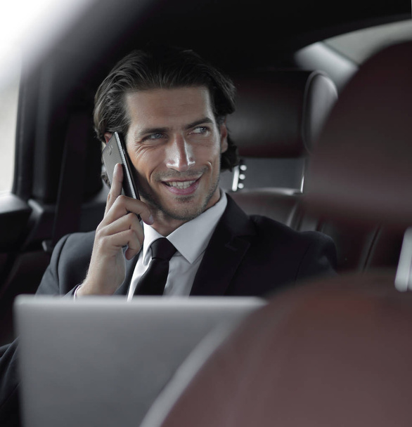 businessman in his car with a laptop talking on the phone - Фото, изображение