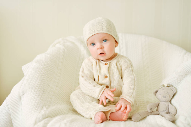sweet baby wearing knitted suit is sitting on the chair - Foto, afbeelding