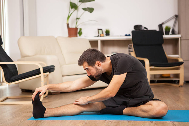 Jeune homme pratiquant le yoga dans son salon
 - Photo, image