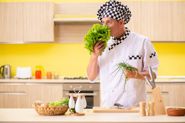 Joven cocinero profesional preparando ensalada en la cocina - Foto, imagen
