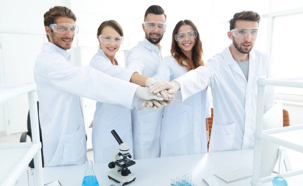 successful team of young scientists with hands clasped together. - Foto, immagini