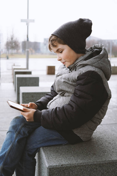 7 χρονών αγόρι με smartphone σε εξωτερικούς χώρους το χειμώνα - Φωτογραφία, εικόνα