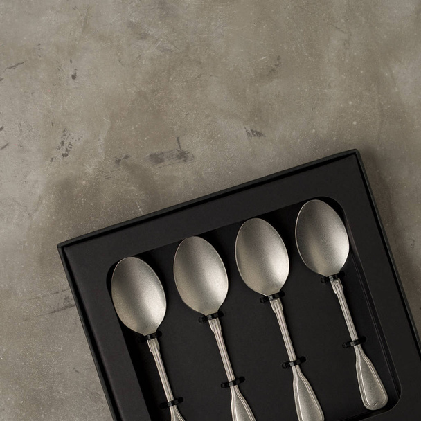 Top view of silver collection of tablespoons teaspoons in black box on gray concrete background - Fotografie, Obrázek