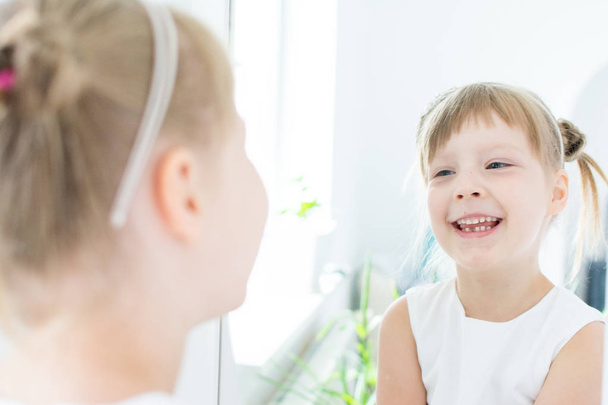 Malá dívka v bílých šatech ztrácí svůj první zub - Fotografie, Obrázek