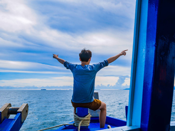 Asian guy sit on the front boat with idyllic ocean and beautiful sky in vacation time,Summer concep - Foto, afbeelding