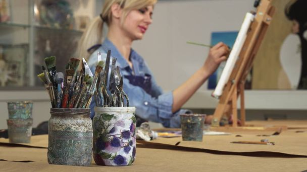 Selective focus on a bunch of paintbrushes female artist working on her painting - Photo, Image