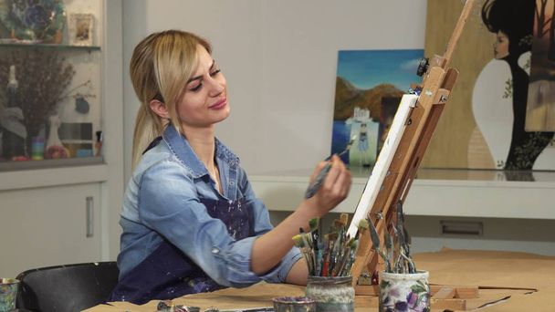 芸術のスタジオで彼女の絵画に取り組んでいる豪華な若い女性アーティスト - 写真・画像