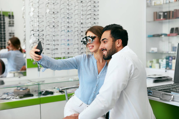 Eye Center. Woman Making Photo On Phone With Doctor On Eye Exam - Foto, imagen