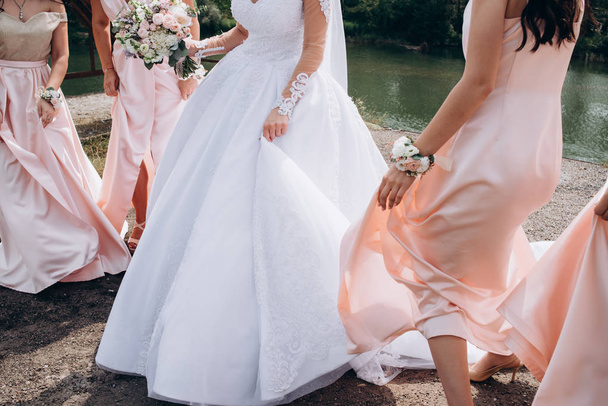 Bridesmaids in pink dresses holding beautiful flowers on hands - Foto, afbeelding