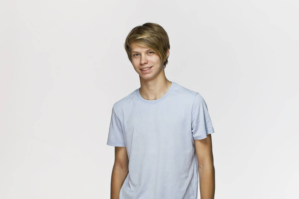 Handsome happy smiling young man wearing blue t-shirt studio portrait against white wall - Foto, Imagen