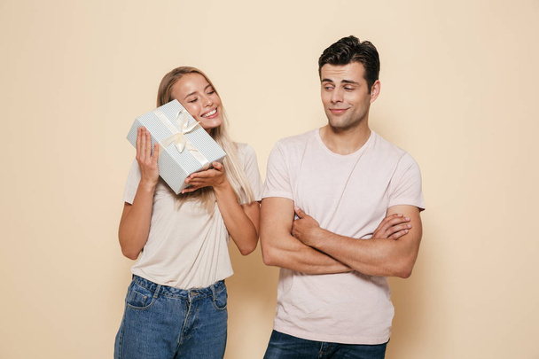 Photo of excited happy young loving couple. Man gives a gift surprise box to his girlfriend isolated. - Φωτογραφία, εικόνα
